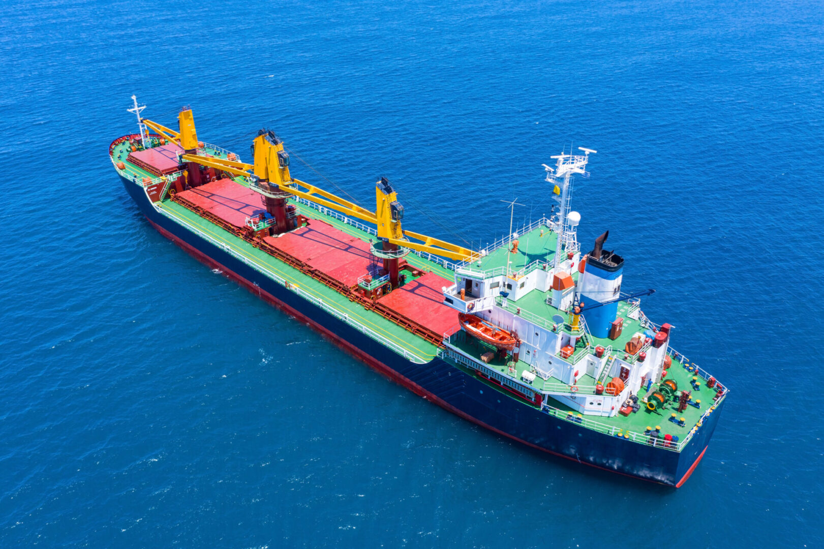 Large Cargo Ship with four Yellow cranes at sea, Aerial image.