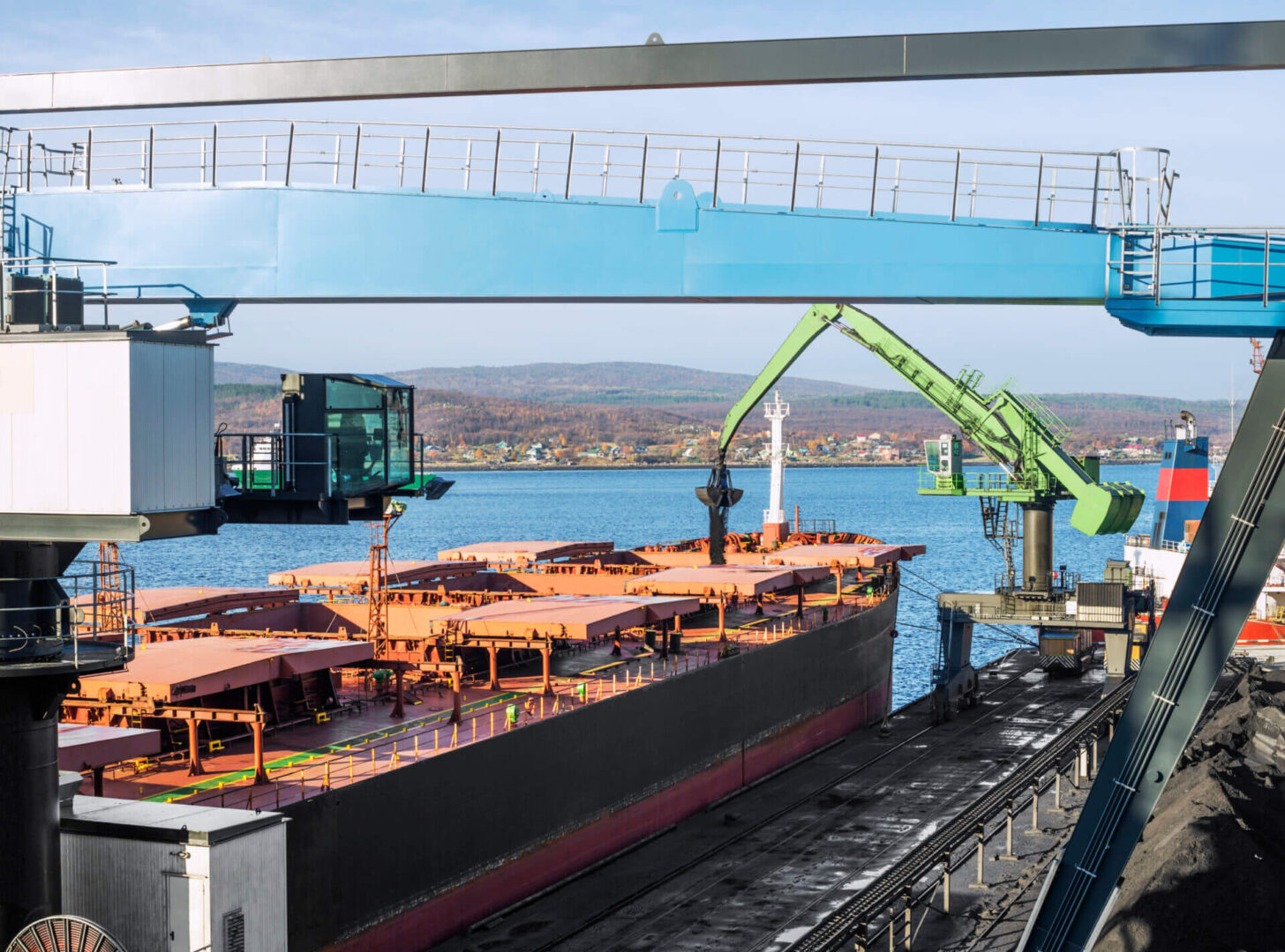 Powerful hydraulic crane - manipulator loads the cargo in the holds of bulk carriers in the port.